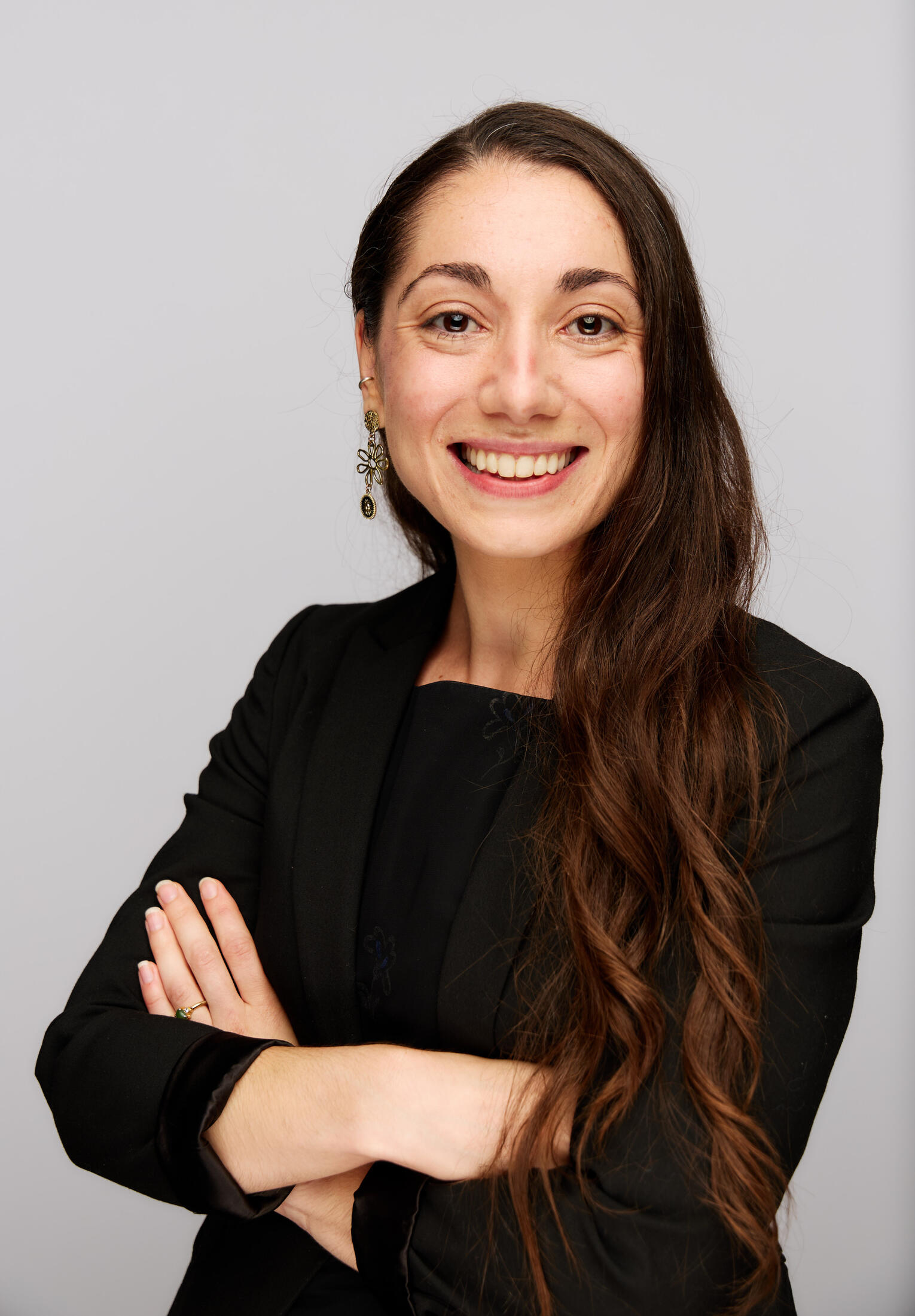 A headshot of Michelle looking at the camera and smiling, with her arms crossed casually in front of her body